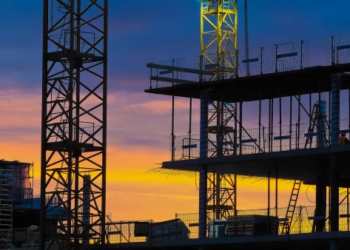 A pre-construction building with a sunset behind it