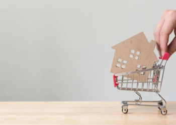 A small cardboard house in a shopping cart.