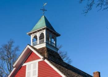 A school bell on top of a historic schoolhouse
