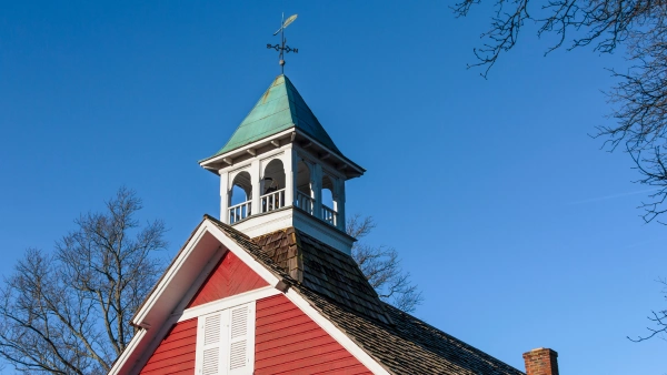 A school bell on top of a historic schoolhouse