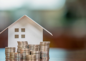 A home with coins piled up in front of it.