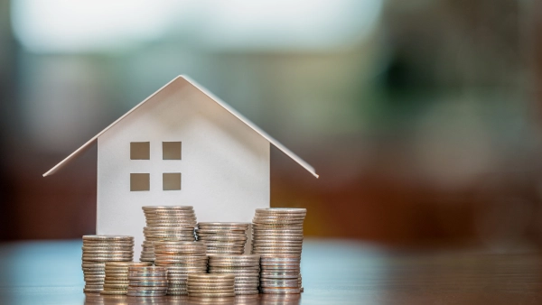 A home with coins piled up in front of it.