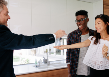 A real estate agent handing over keys to new homeowners.