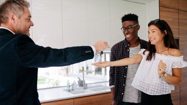 A real estate agent handing over keys to new homeowners.