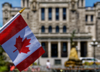 A Canadian flag in front of old building.