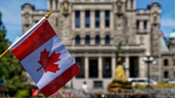 A Canadian flag in front of old building.