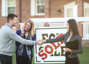 Young happy couple shaking hands with real estate agent