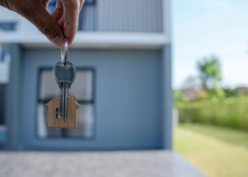 Someone holding keys in front of a home