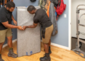 Two movers moving furniture in a home