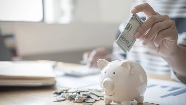 Putting cash into a piggy bank.