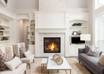 White spacious living room with a couch, two accent chairs and a fireplace