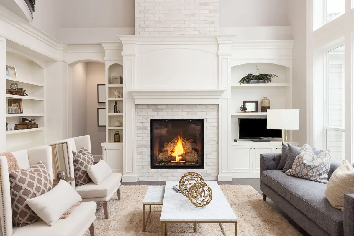 White spacious living room with a couch, two accent chairs and a fireplace