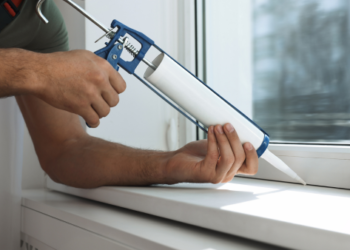 A guy sealing a window.