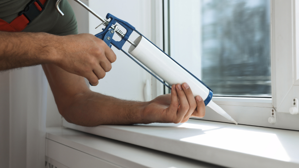 A guy sealing a window.