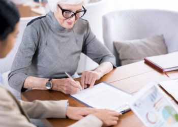 An old lady writing on a piece of paper.