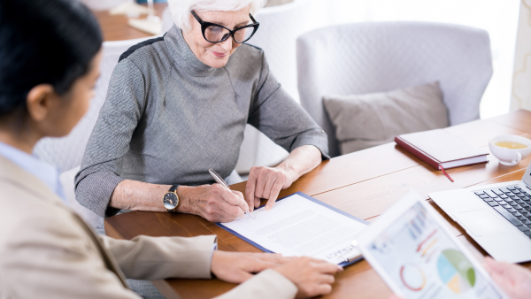 An old lady writing on a piece of paper.