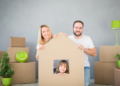 A family poses with a cardboard box that is cut into the shape of a house