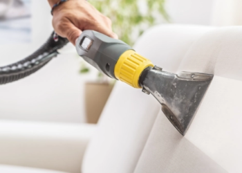 A vacuum cleaning dust off a couch.