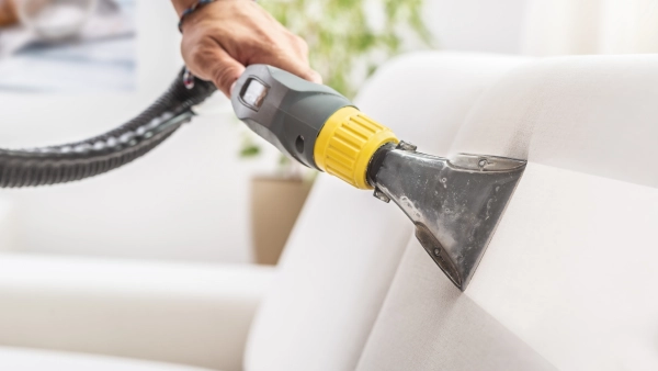 A vacuum cleaning dust off a couch.
