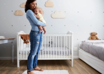 A mother holding a baby to her chest in a decorated nursery.