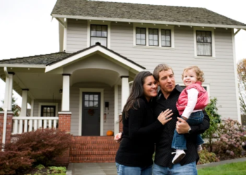 A family of three standing in front of a detached home.