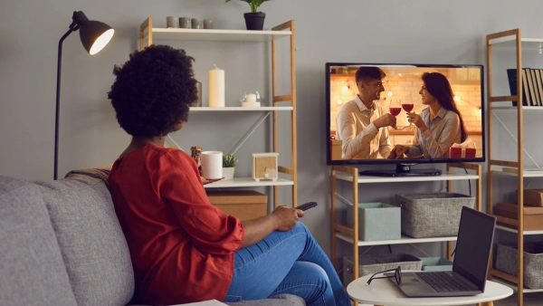 A woman watching a reality tv show in her living room.