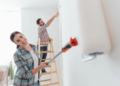 A woman and man painting a wall in their home
