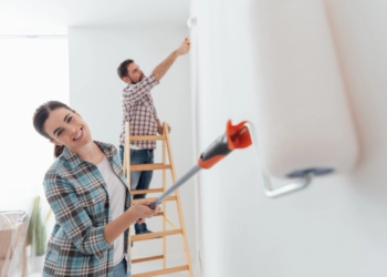 A woman and man painting a wall in their home