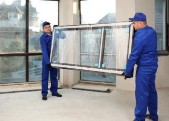 Two repairmen carrying a new window