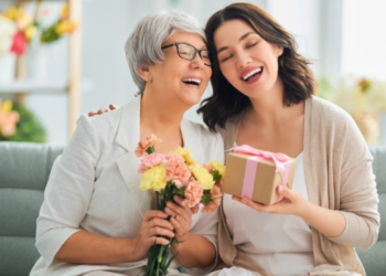 A mother and daughter laugh together while exchanging gifts