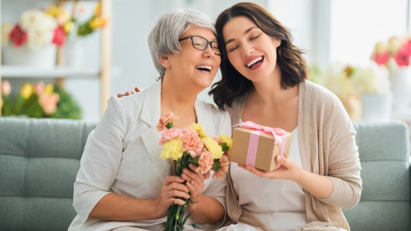 A mother and daughter laugh together while exchanging gifts