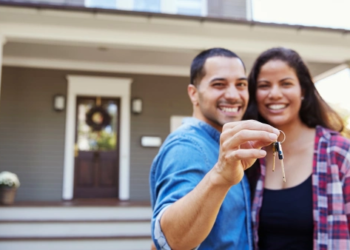 A couple holding house keys in front of their new home