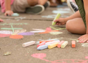 Kids playing with colourful chalk outside.