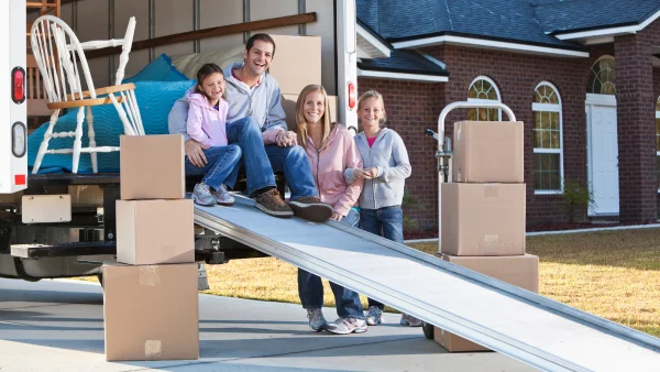 A family smiling in a moving truck with moving boxes