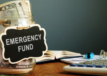 A glass jar full of money and labelled 'emergency fund'