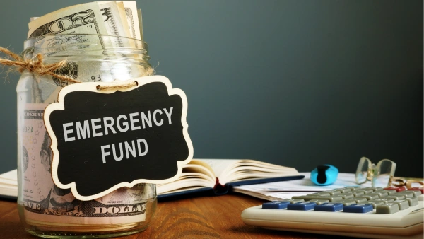 A glass jar full of money and labelled 'emergency fund'