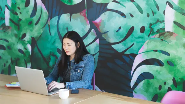 Woman using laptop behind a bright mural