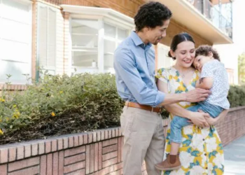 Parents holding young child outside apartment building