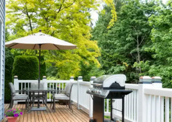 A picture of a deck with a grill and table