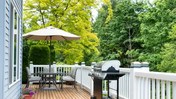 A picture of a deck with a grill and table