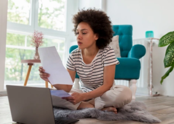A woman staring at a paper with her laptop