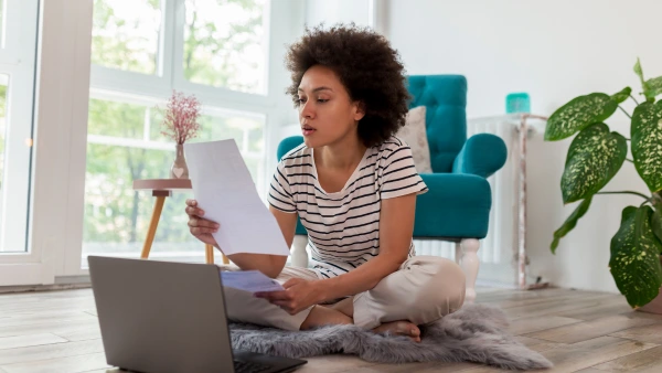 A woman staring at a paper with her laptop