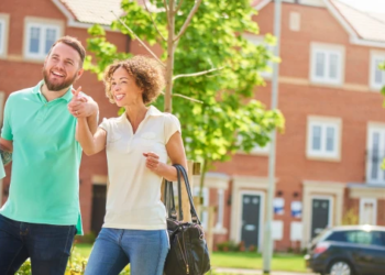 Two first-time home buyers stand on the street looking at homes
