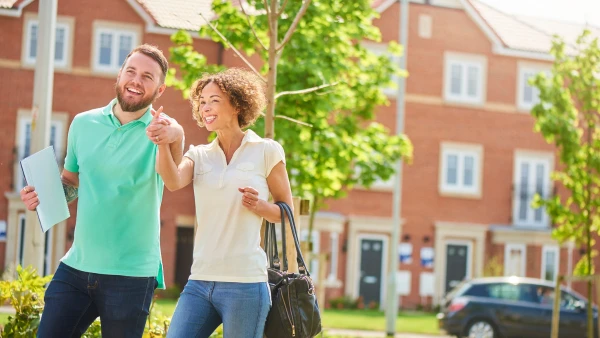 Two first-time home buyers stand on the street looking at homes