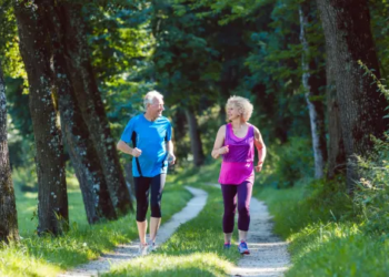 An older couple running together in a park