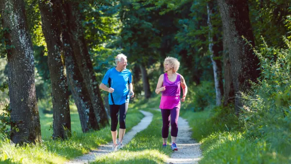 An older couple running together in a park