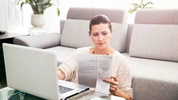 A woman looks at financial statements at a computer desk.