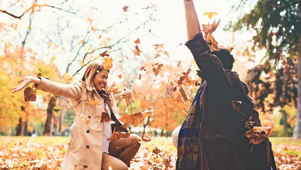 Two people surrounded by orange, fall leaves.