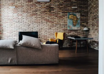 A living room featuring brick walls, 2 sofas, a TV and a table.