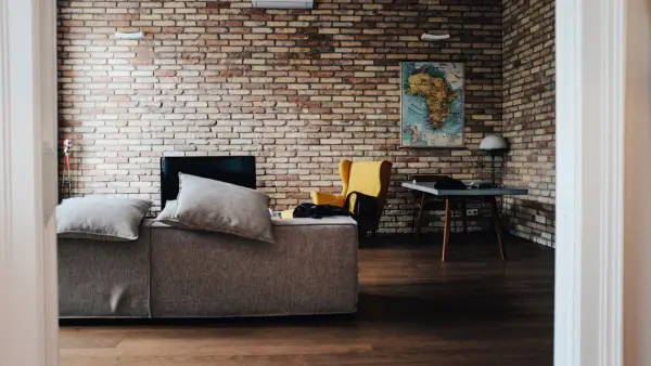 A living room featuring brick walls, 2 sofas, a TV and a table.
